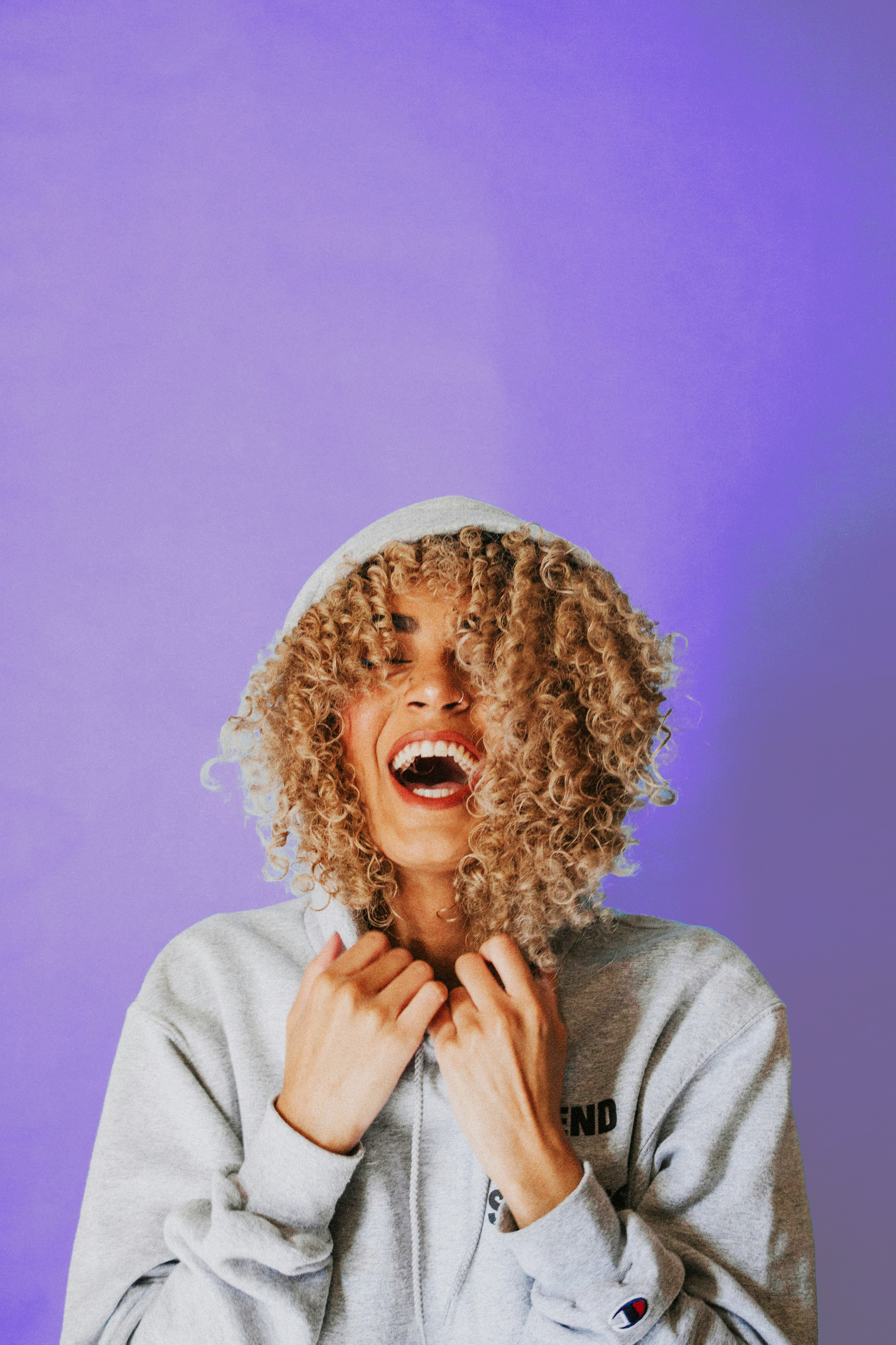 A young sheep in a sweater and hood with golden fur is laughing